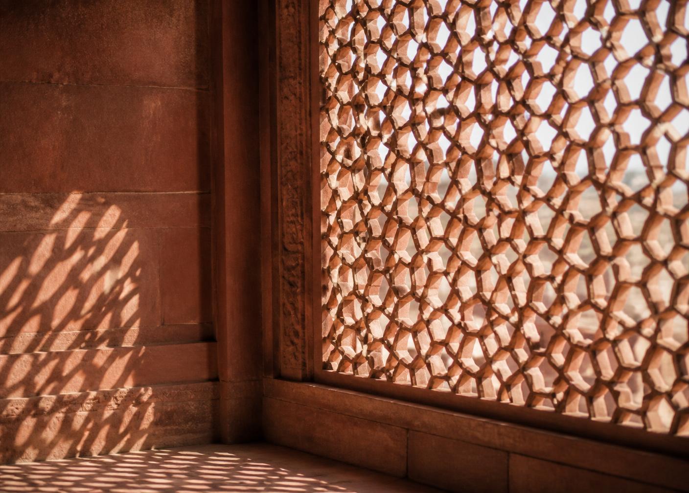 Carved sandstone jali screen casting geometric shadow