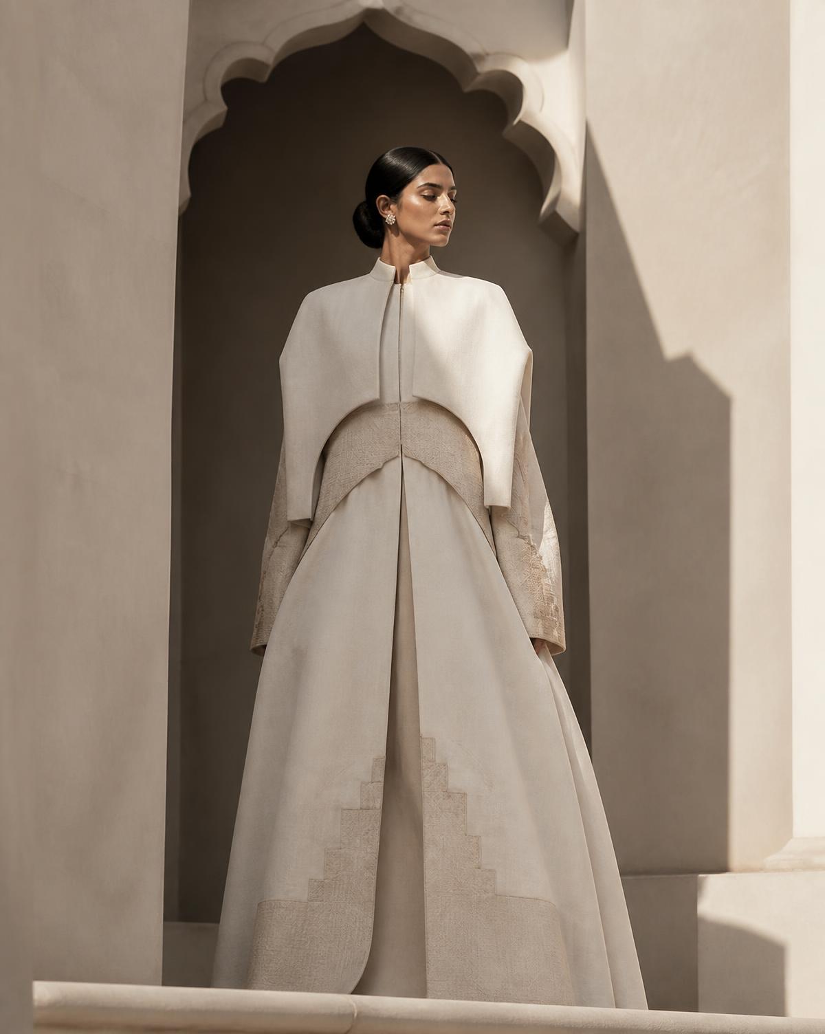 Structured ivory garment framed by a carved stone arch