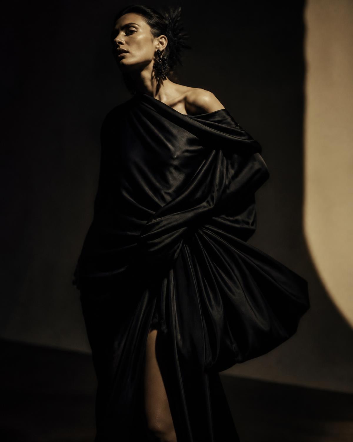 Black silk drapery sculpted across a couture silhouette in low light